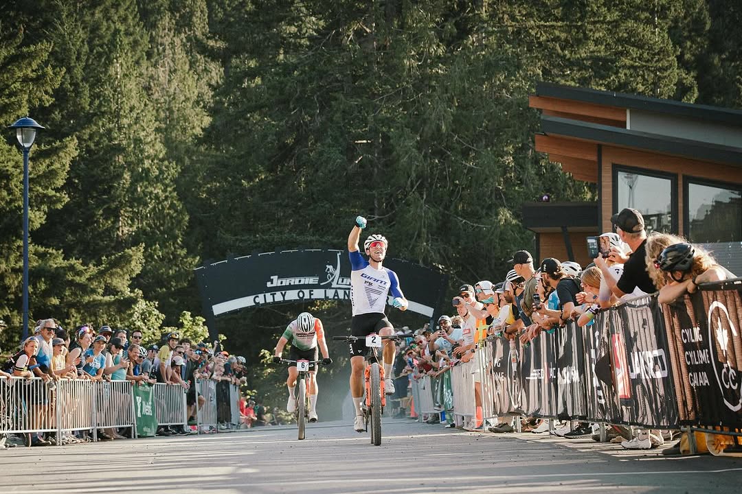 Carter Woods celebrating with a wheelie at the finish line, crowd cheering